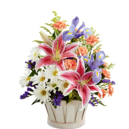 Mixed bouquet with pink lilies, purple irises, and white daisies in a basket