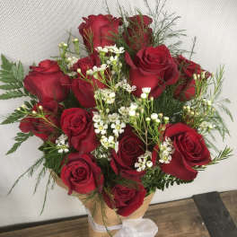 Bouquet of red roses with white filler flowers in brown paper wrap