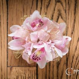 Pink orchid corsage with ribbon on a wooden surface