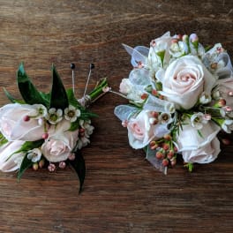Two small rose boutonnieres with white filler flowers and ribbon accents