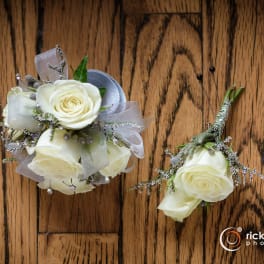 White rose boutonniere and small matching floral cluster on a wood surface