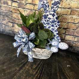 Green houseplants in a white basket with blue patterned bunny and egg decorations