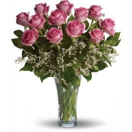 Arrangement of pink roses with white filler flowers in a clear glass vase