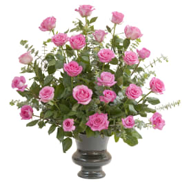Pink roses arranged in a dark vase with airy greenery