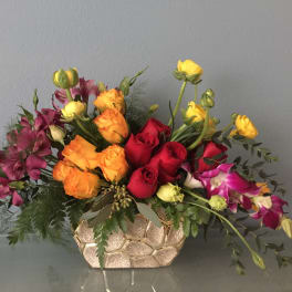 Mixed bouquet of roses and orchids in a gold textured vase