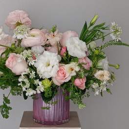 Pink and white flower arrangement in a purple glass vase