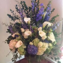 Tall floral arrangement with white calla lilies and purple blooms