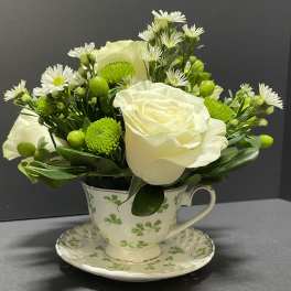 White roses and green button mums arranged in a teacup vase