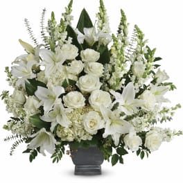White lilies and roses arranged in a dark urn vase