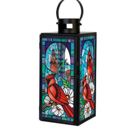 Black metal lantern with stained-glass cardinal and white flowers in bright jewel tones.