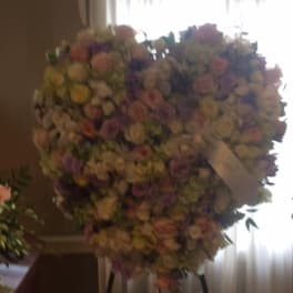 Large heart-shaped floral spray on a stand with pastel roses and mixed blooms