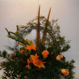 Orange lilies and roses in a low floral arrangement with greenery