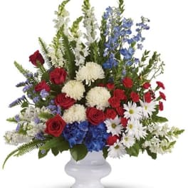 Large mixed flower arrangement in a white vase with red, white, and blue blooms