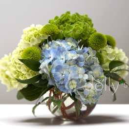 Blue and green hydrangea bouquet with green pompon mums in a glass vase