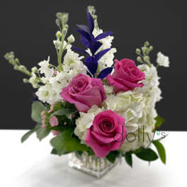 Pink roses and white flowers arranged in a clear square vase