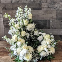Open wreath of white and cream roses, mums, carnations, and tall white blooms arranged asymmetrically