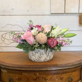Pink and white floral arrangement in a patterned ceramic container
