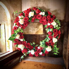 Circular wreath of red and white roses with ivy greenery