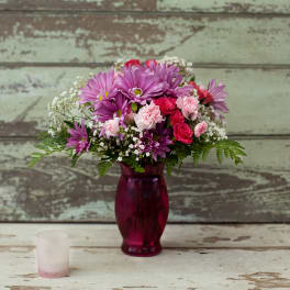 Pink and purple mixed bouquet in a magenta glass vase