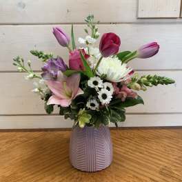 Pink and purple tulips with white daisies in a lavender vase