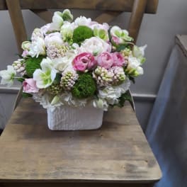 Pink and white floral arrangement in a white square vase