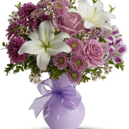 Pink and white bouquet in a lavender vase with a ribbon