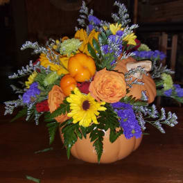 Fall floral arrangement in a pumpkin container with sunflowers and roses