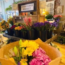 Bouquet of pink and yellow daisies with lilies in brown paper