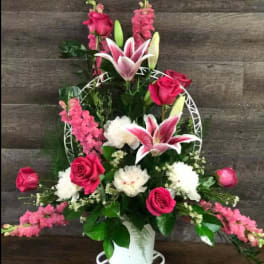 Pink and white floral arrangement in a white vase with a decorative frame