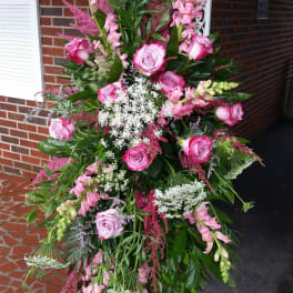 Tall standing spray of pink roses and snapdragons with white filler flowers