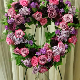 Heart-shaped floral wreath of pink and purple roses on a stand