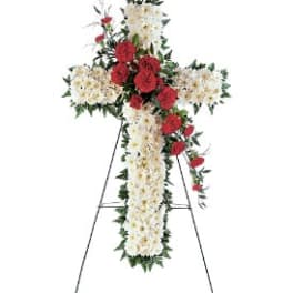 Cross-shaped floral funeral spray with red and white flowers on an easel