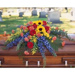 Colorful flower spray on a wooden casket in a cemetery