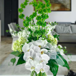 White orchids and green flowers in a clear glass vase