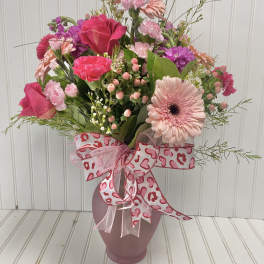 Pink mixed bouquet in a vase with a heart-patterned ribbon