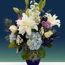 White lilies and blue hydrangeas in a blue vase