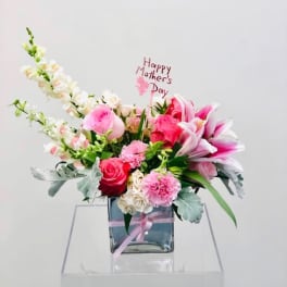 Pink and white floral arrangement in a glass vase with a Mother's Day sign