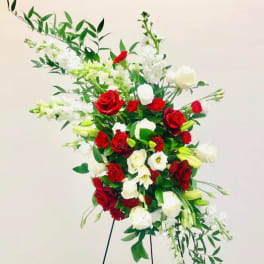 Tall standing arrangement of red and white roses with white lilies and greenery