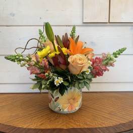 Mixed bouquet in a floral ceramic pot with roses, lilies, and snapdragons