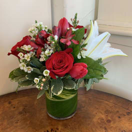 Red roses and white lilies arranged in a green glass vase
