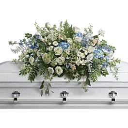 White and blue floral casket spray on a white coffin