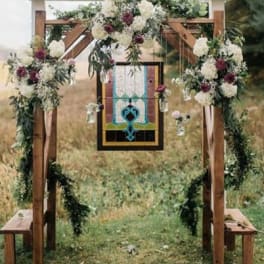 Floral-decorated wooden wedding arch with hanging glass jars
