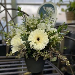 White flowers arranged in a black pot with greenery