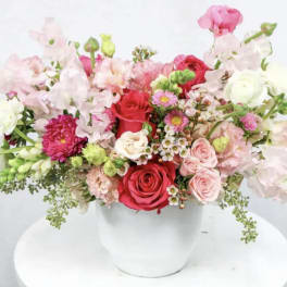 Mixed pink and red flower arrangement in a white vase