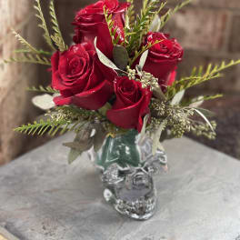 Red roses arranged in a small glass skull vase