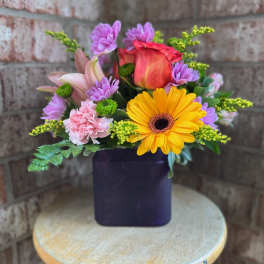 Mixed bouquet in a dark square vase with a yellow gerbera and pink rose