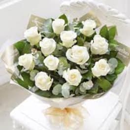 Bouquet of white roses with greenery wrapped in paper
