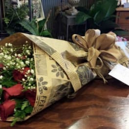 Bouquet of red roses and baby's breath wrapped in brown paper with a ribbon