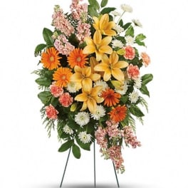 Standing floral spray with yellow lilies, orange daisies, and pink flowers