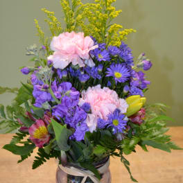 Mixed bouquet in a glass vase with pink, purple, and yellow flowers